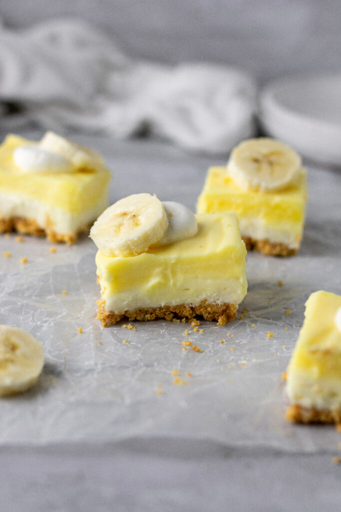 Banana cream cheesecake bars sitting on parchment paper.