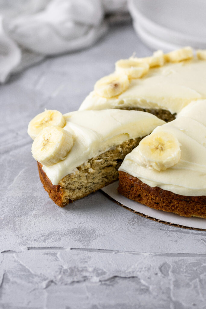 one layer banana cake with cream cheese frosting and fresh bananas on top