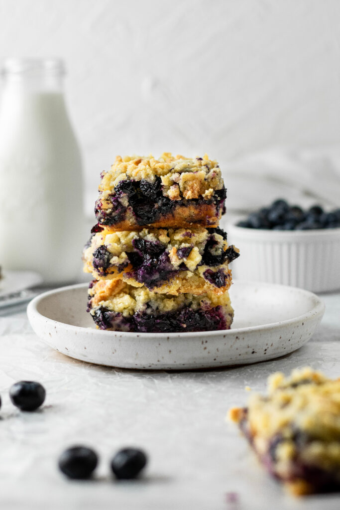 blueberry crumble bars stacked high on a plate