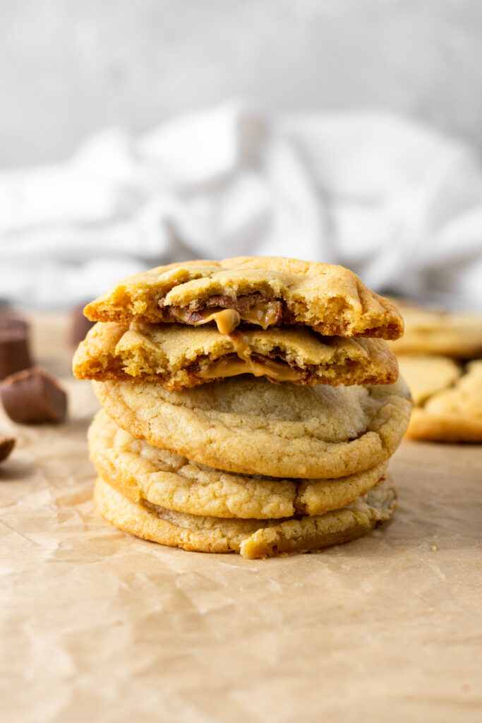 rolo stuffed cookies inside of a brown sugar cookie dough. Ooey gooey caramel and chocolate are oozing out of the center of the cookies