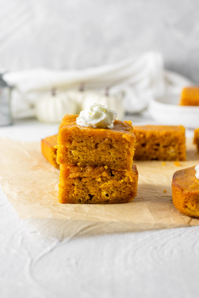 pumpkin spice bars stacked on top of each other and covered with a dollop of whipped cream