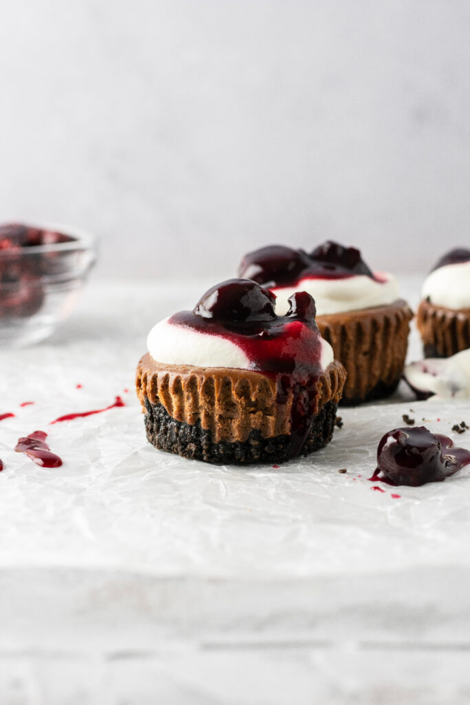 black forest mini cheesecakes with whipped cream and dark red cherries