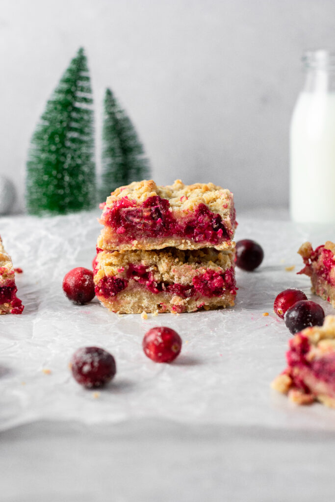 Cranberry shortbread bars stacked on top of each other with fresh berries off to the side.
