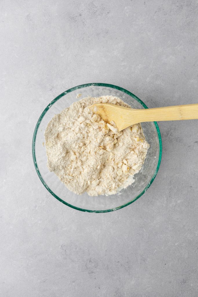 A wooden spoon mixing together dry ingredients.