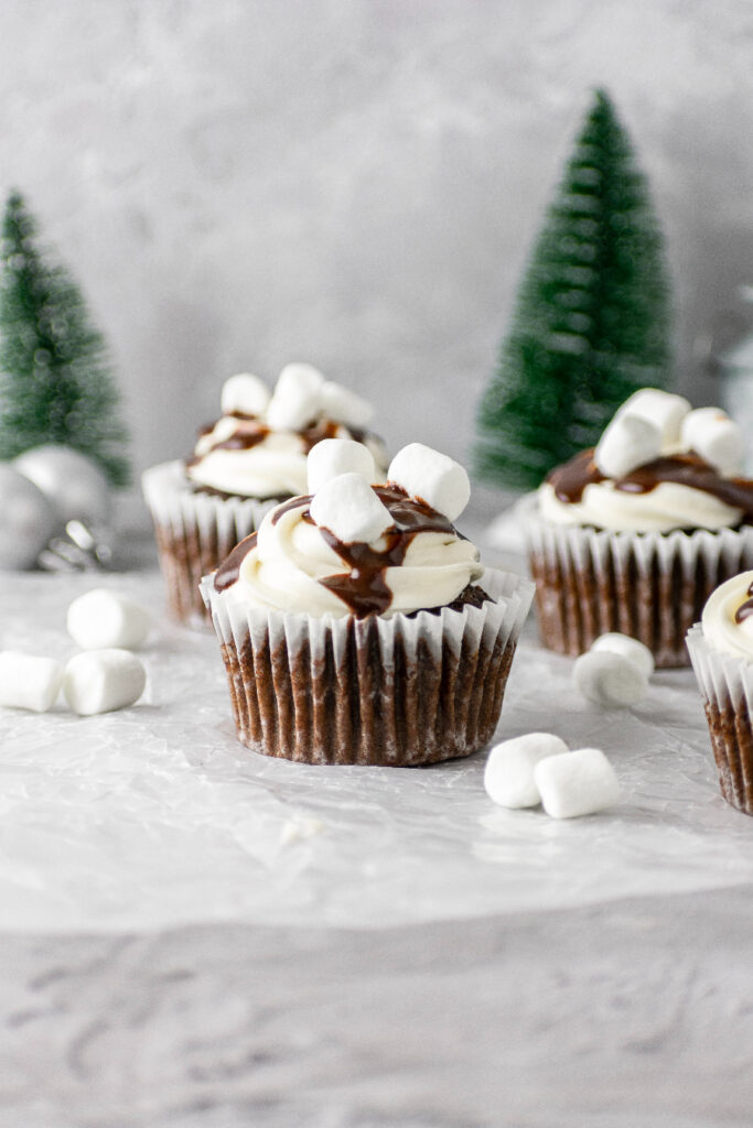 Hot cocoa cupcakes with a chocolate drizzle and mini marshmallows.