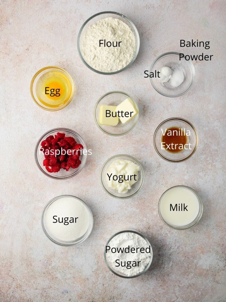 list of ingredients: flour, baking powder, salt, egg, butter, raspberries, vanilla extract, yogurt, sugar, milk, and powdered sugar.