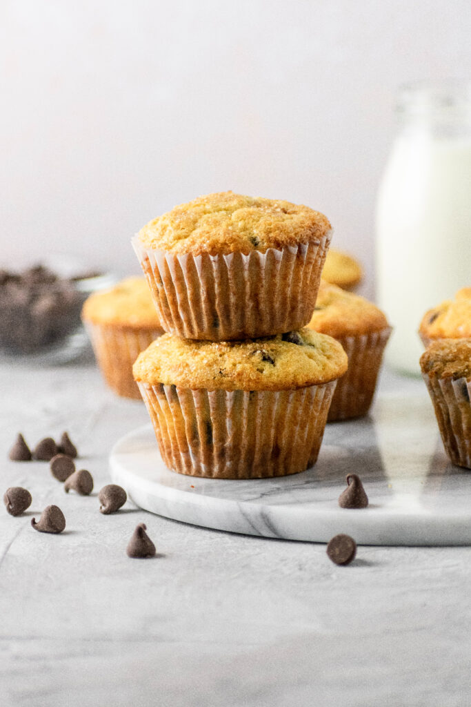 Muffins stacked on top of each other with chocolate chips scattered everywhere.
