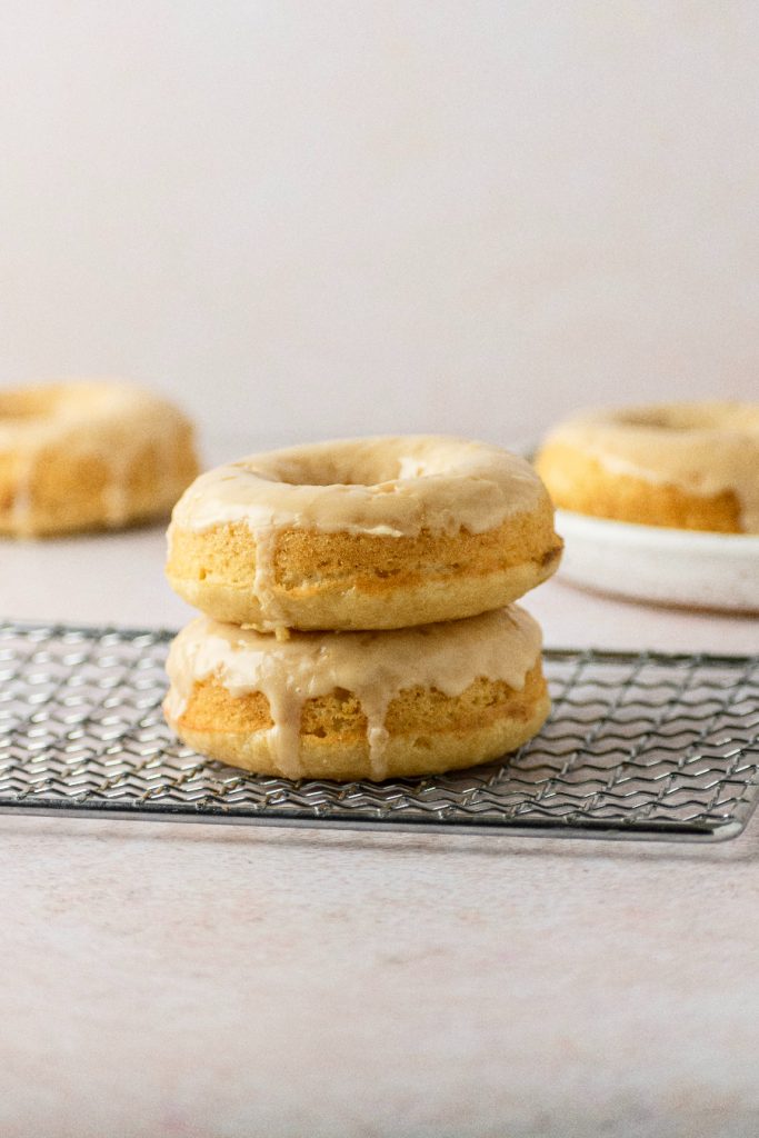baked maple donuts stacked on top of each other sitting on a tray