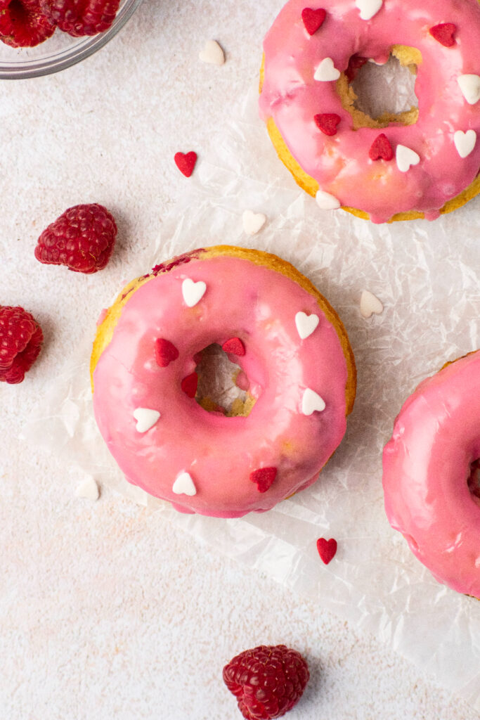 raspberry glazed donuts with fresh red berries and sprinkled with hearts.