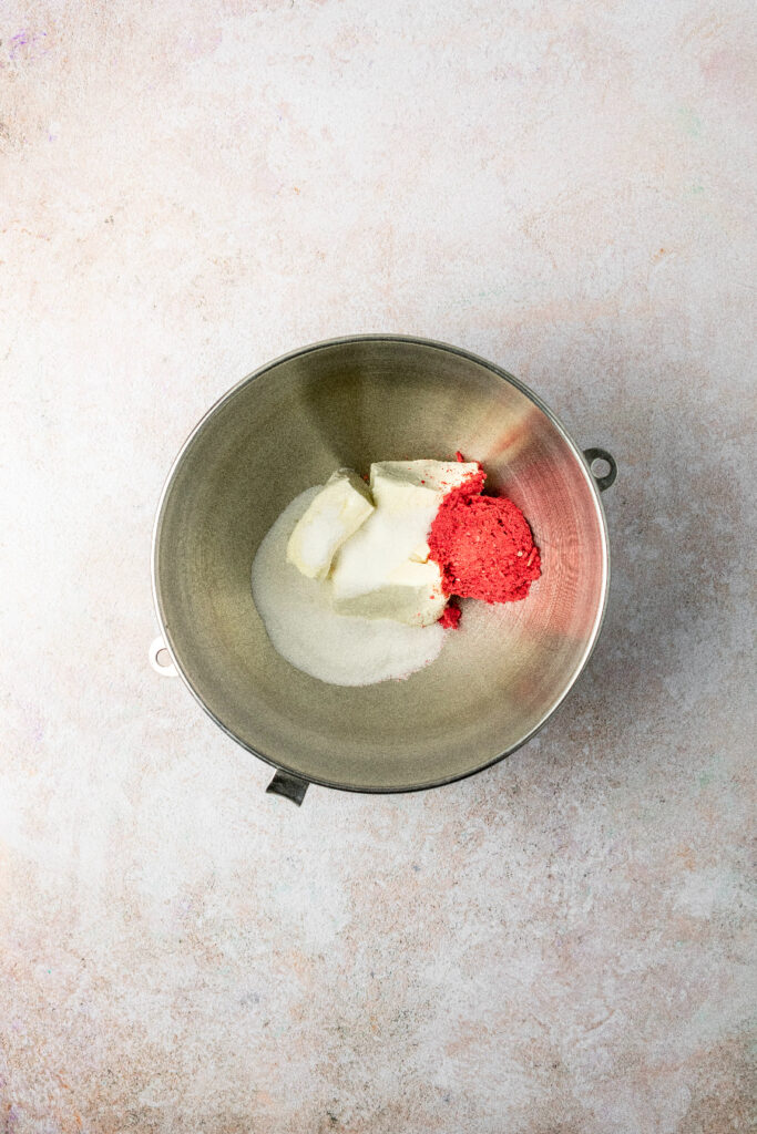 stand mixer bowl with cream cheese, sugar, and freeze dried strawberries.