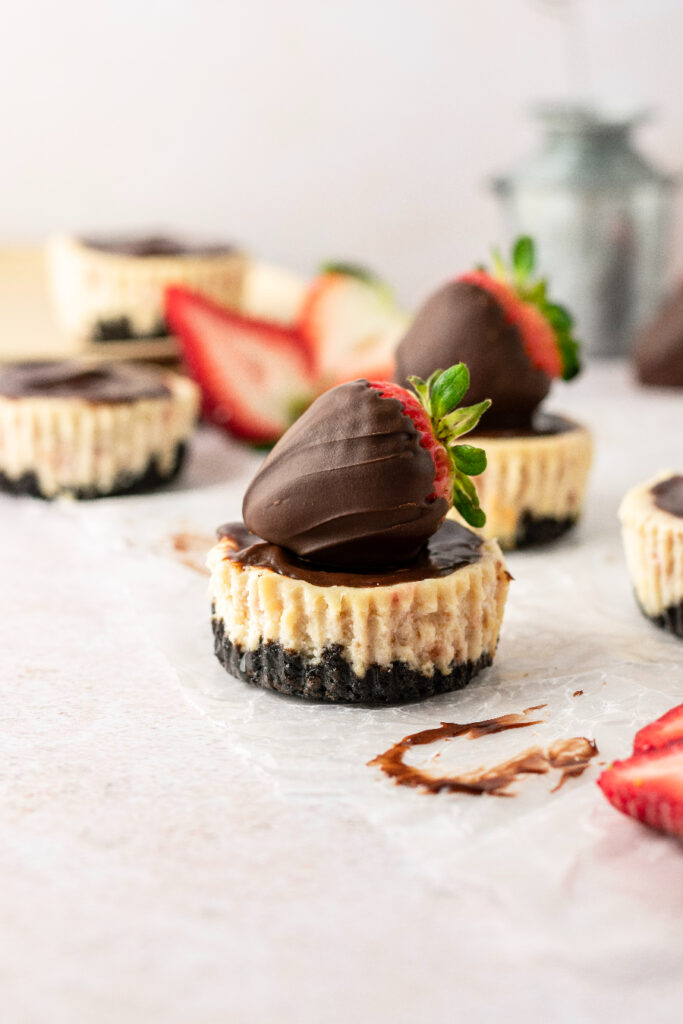 strawberry cheesecakes with a chocolate crust and plated with strawberries.