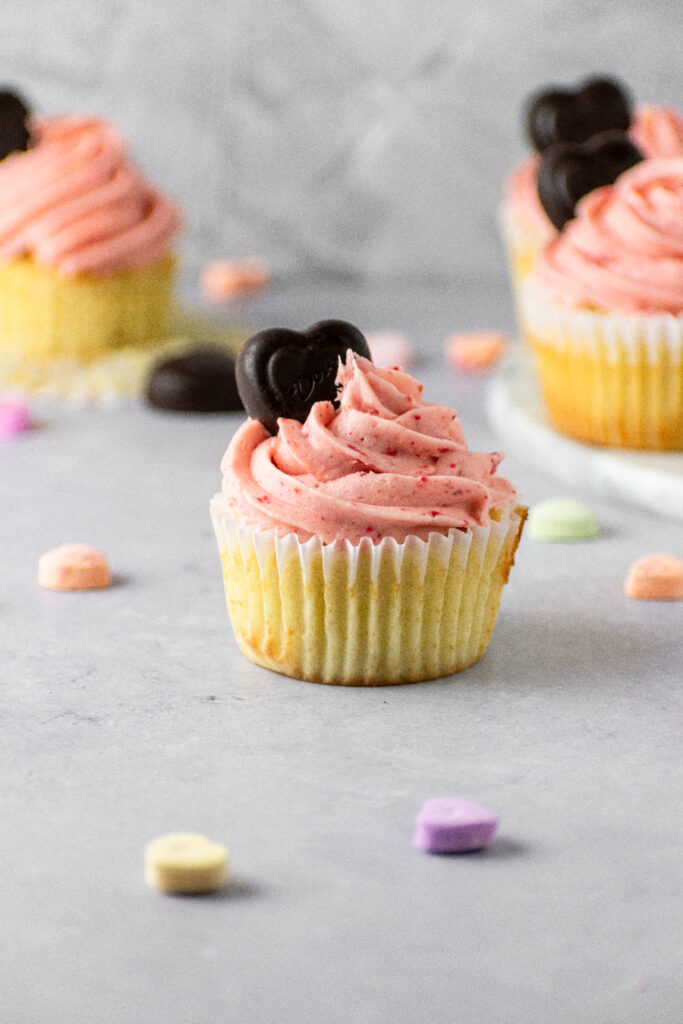 strawberry frosted cupcakes surrounded by colorful conversation hearts.