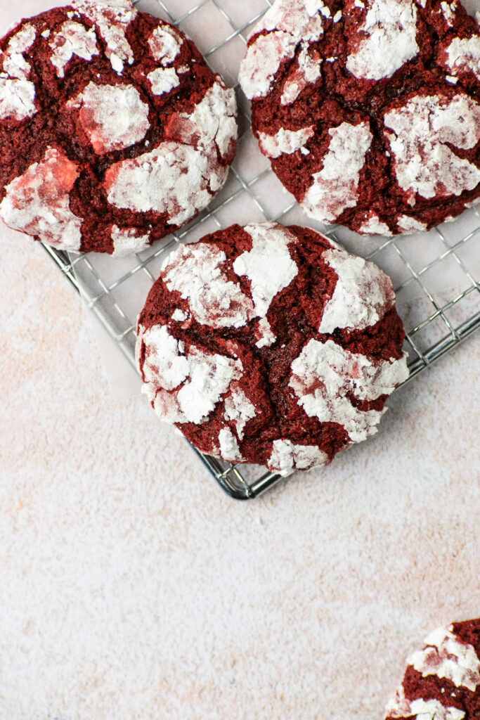 Red velvet cookies sitting on a wire rack with parchment paper.