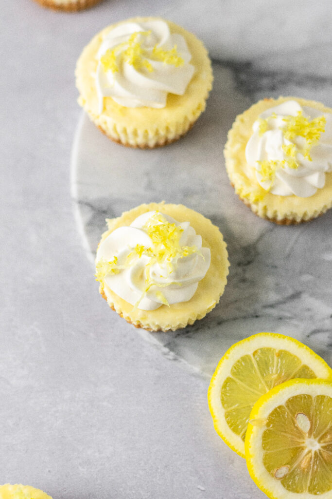 lemon mini cheesecakes topped with whipped cream and zest.
