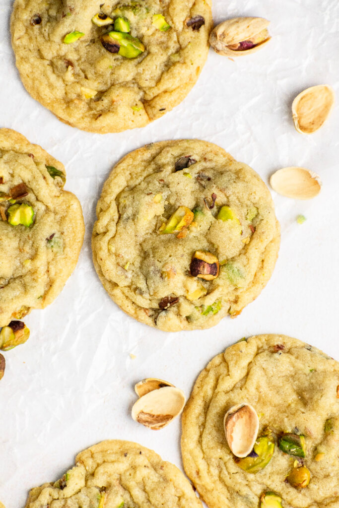 Super chewy pistachio cookies with shells on top of the parchment paper.