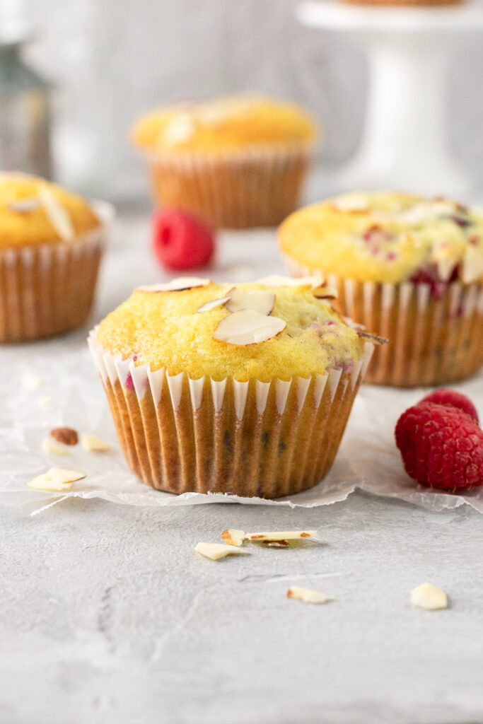 A straight on view of raspberry muffins with almond slices.