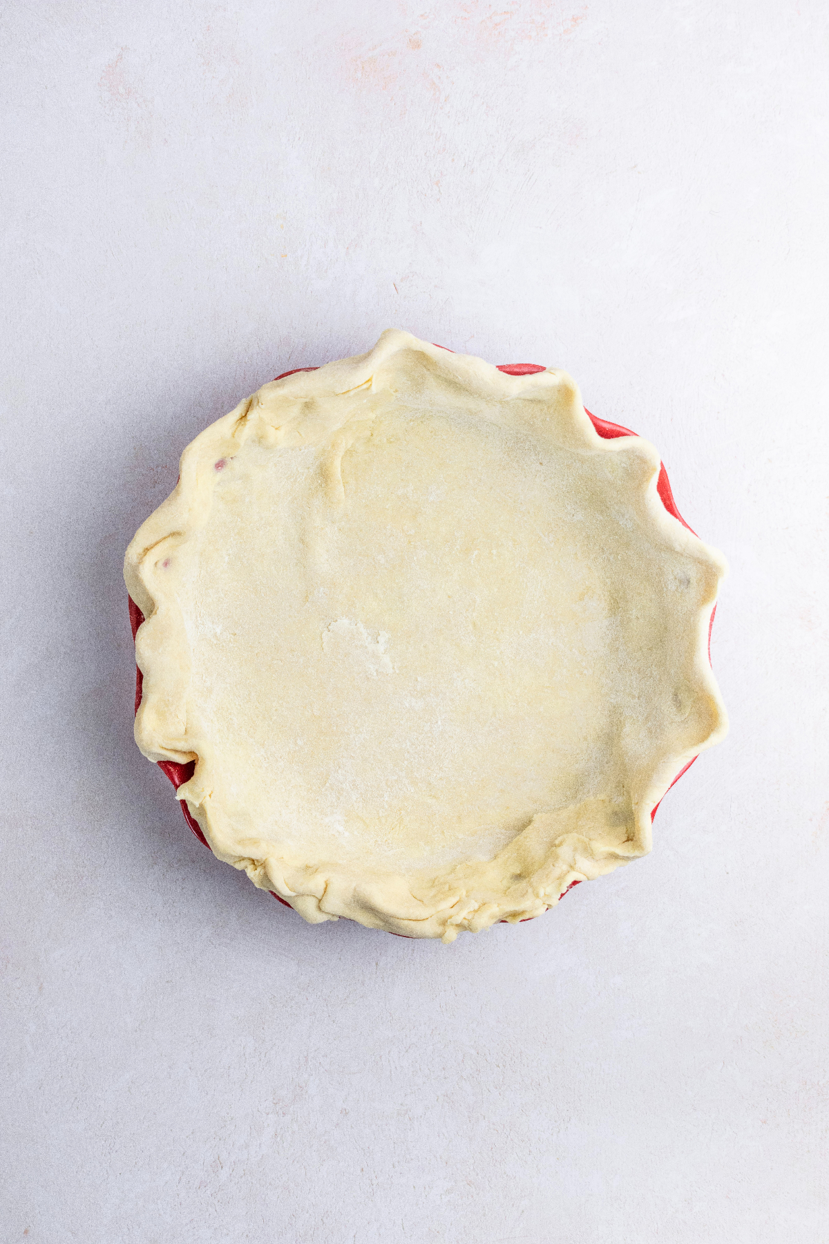 Pie dough in a red pie plate.