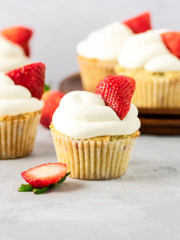 A half dozen of strawberry cupcakes with fresh whipped cream.