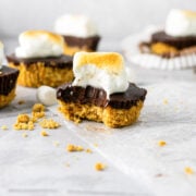 A bite taken out of a chocolate mini pie with graham cracker crumbs.