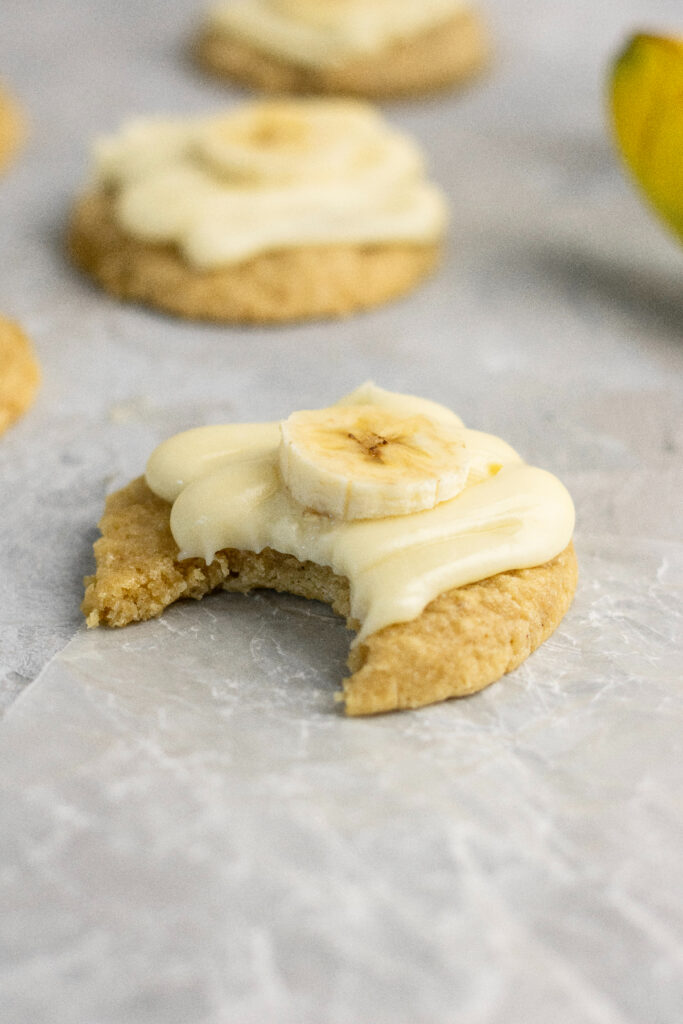 A bite taken out of a banana cookie with frosting.
