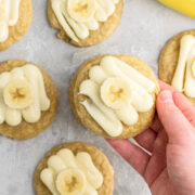 A hand holding frosted banana cookies.