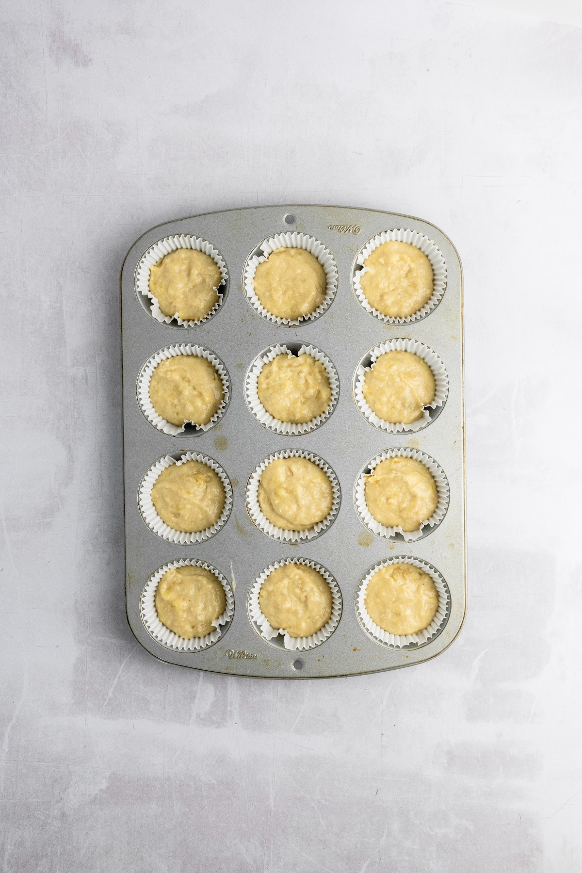 A 12 count muffin pan filled with cake batter.