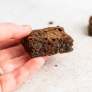 A hand holding a super fudgy brownie.