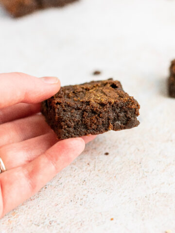 A hand holding a super fudgy brownie.