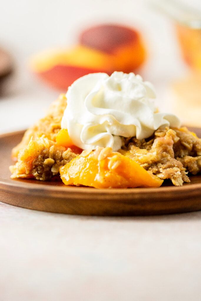 Homemade peach crisp with whipped cream on top.