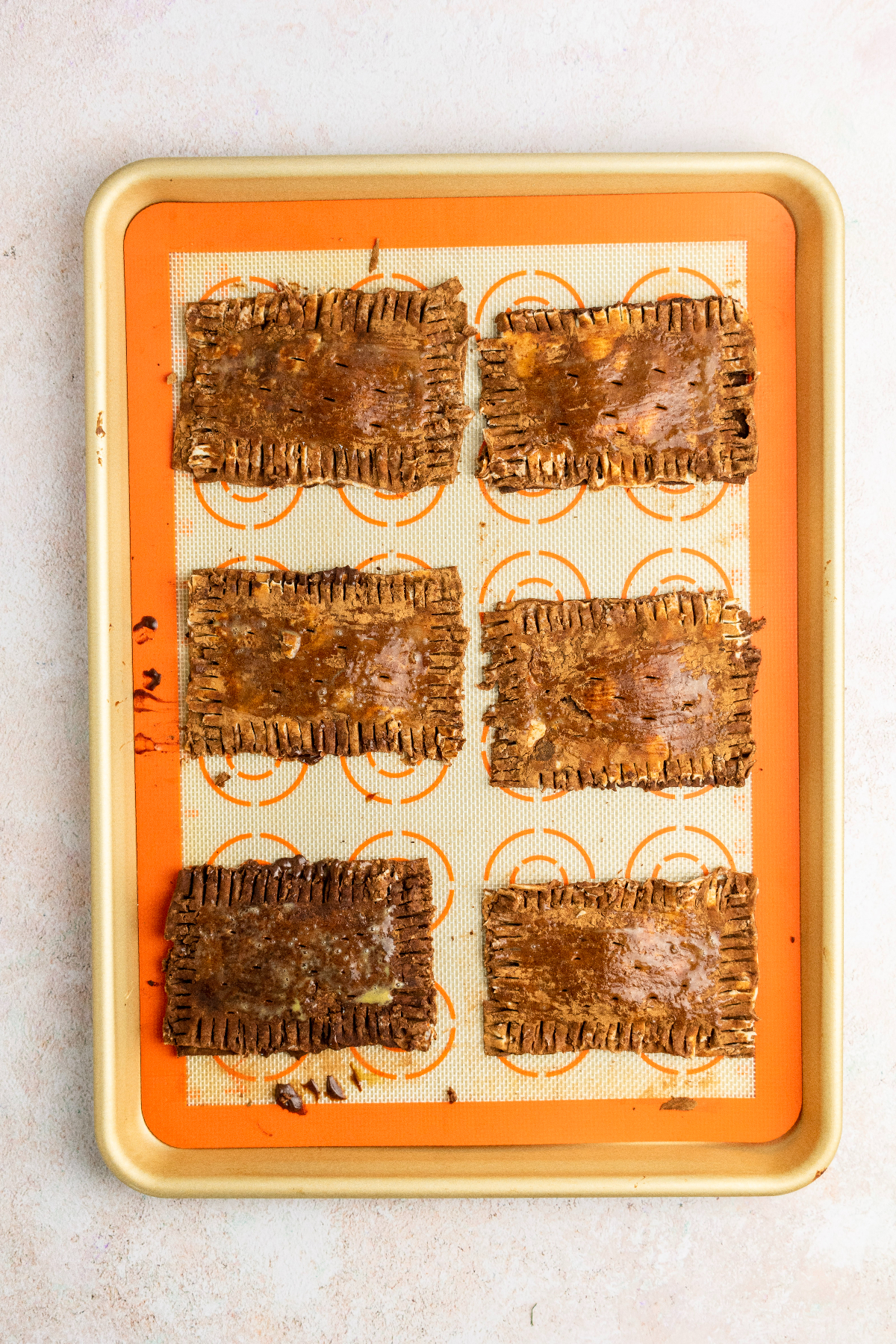 Six pop tarts sealed on a baking sheet.