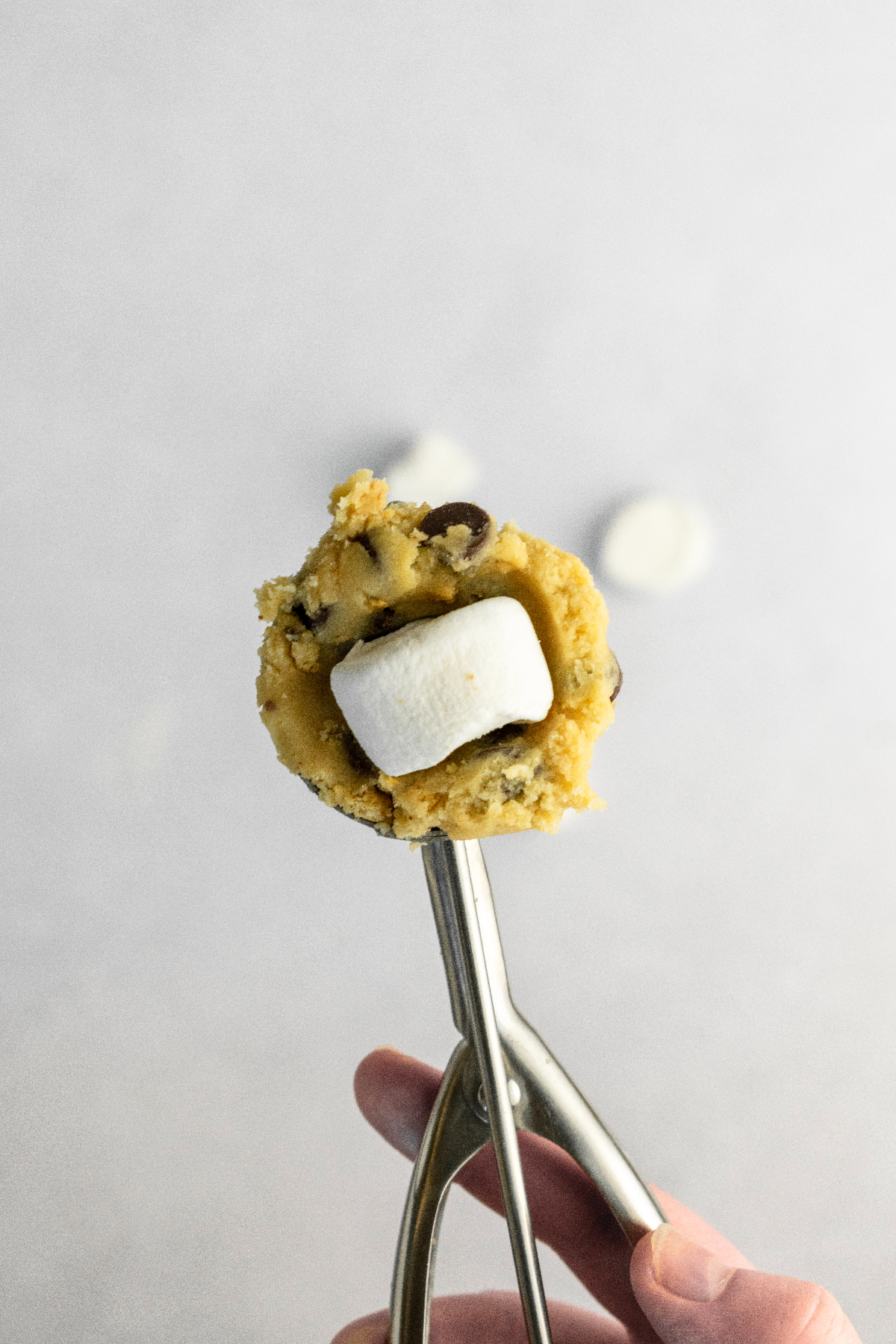 Cookie scoop with cookie dough and a marshmallow.