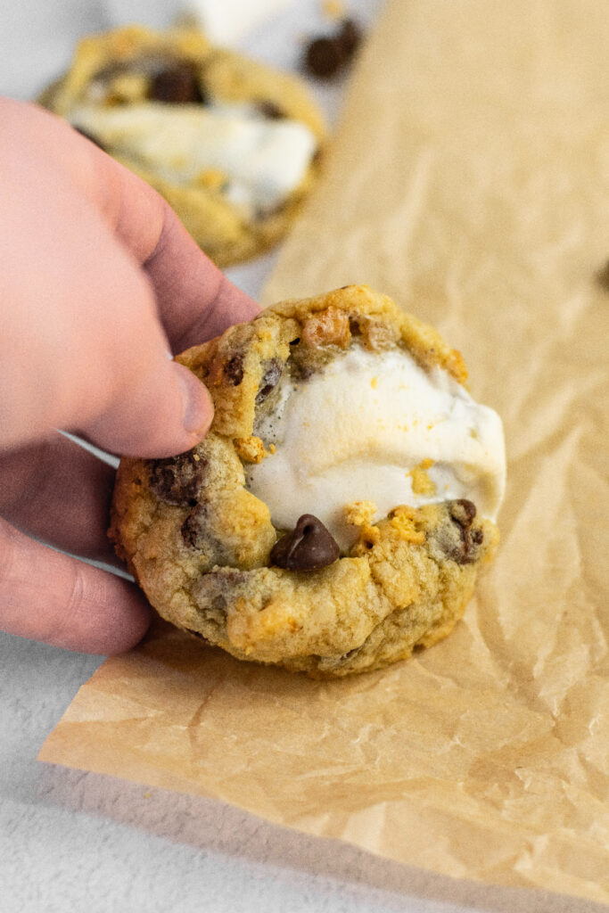 A hand holding a s'mores chocolate chip cookie.