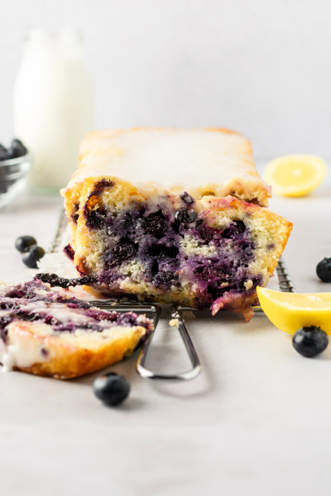 Two slices of lemon bread filled with fresh blueberries on a wire plate.