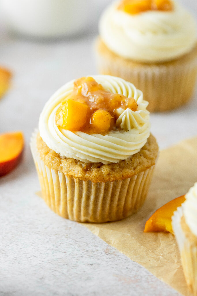 A close up look of the peach pie filling on top of a brown sugar cinnamon cupcake.