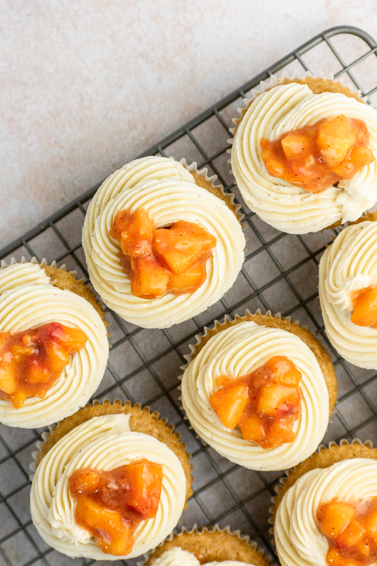 Cupcakes frosted and topped with more peaches.
