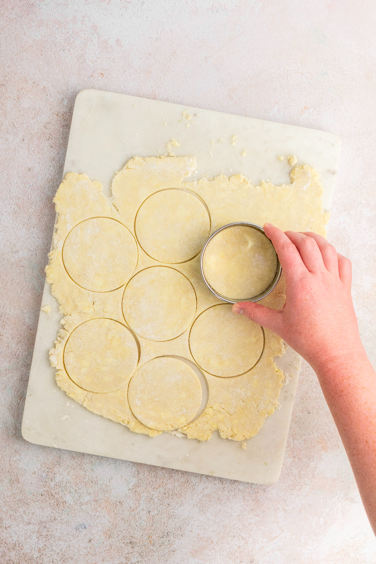 Cutting out pie dough into circles using a cookie cutter.