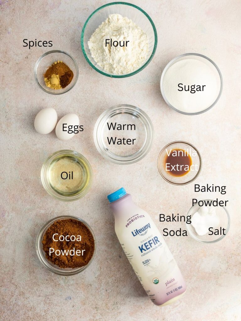 Ingredients needed: flour, sugar, spices, eggs, warm water, vanilla, oil, baking powder, baking soda, salt, cocoa powder, and milk.