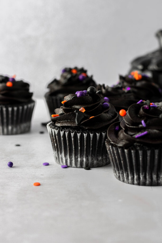 Black velvet cupcakes with black frosting and orange, purple, and black sprinkles.