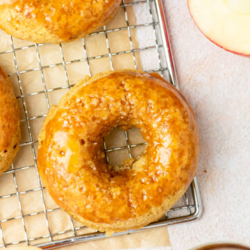 Caramel apple baked donuts on a wired rack with honey crisp apples and more caramel.