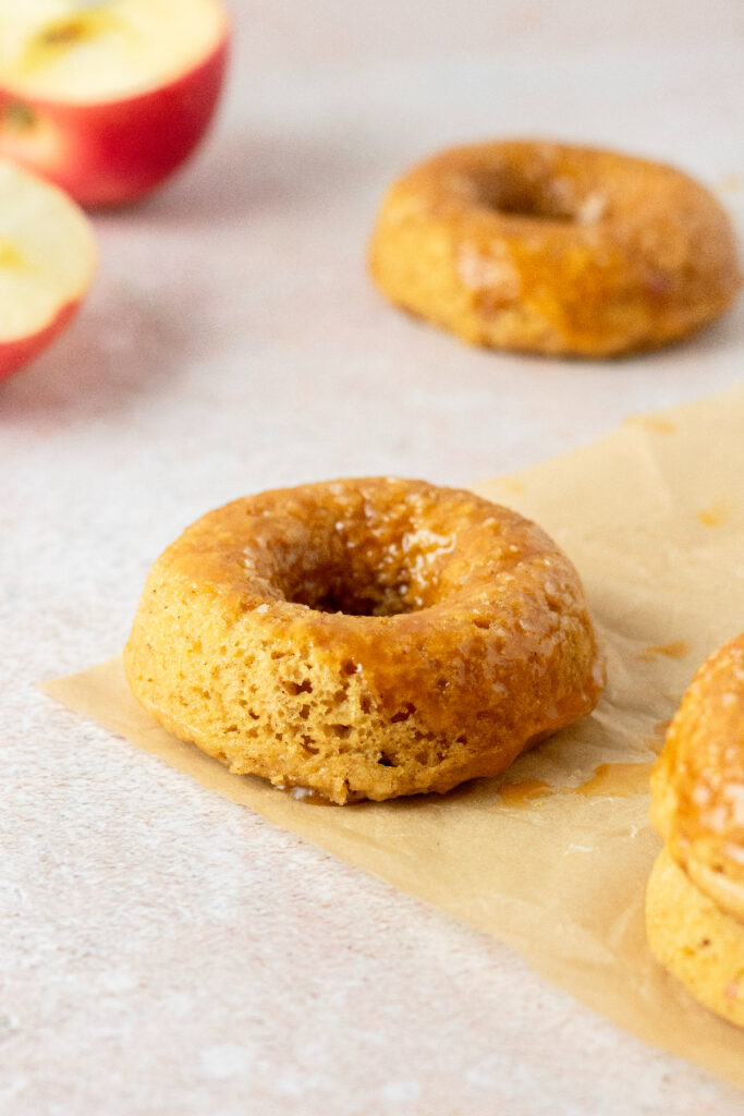 Apple donuts on a brown piece of parchment paper.