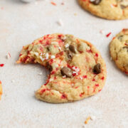 Chocolate chip cookie with a bite taken out of it and silver ornaments in the back.