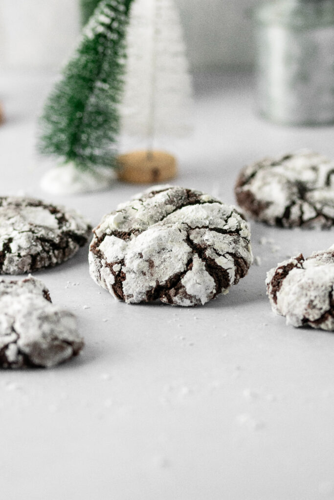 Double chocolate crinkle cookies with small Christmas trees in the background.