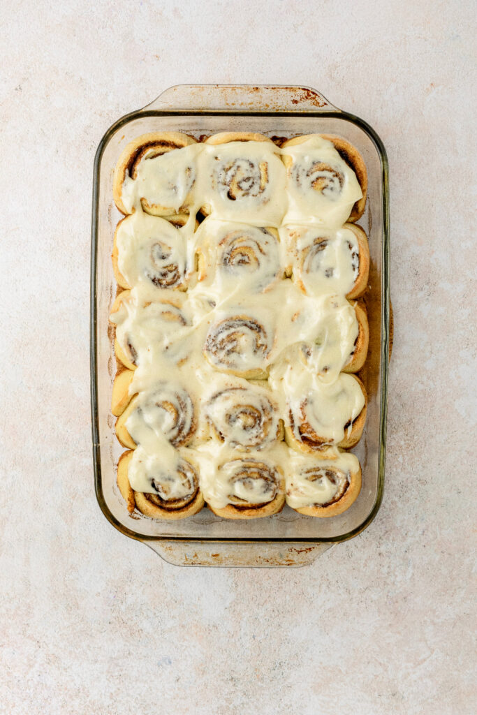 Frosted cinnamon rolls in a baking pan.