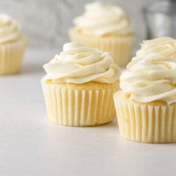 Vanilla cupcakes with vanilla buttercream swirled on top.