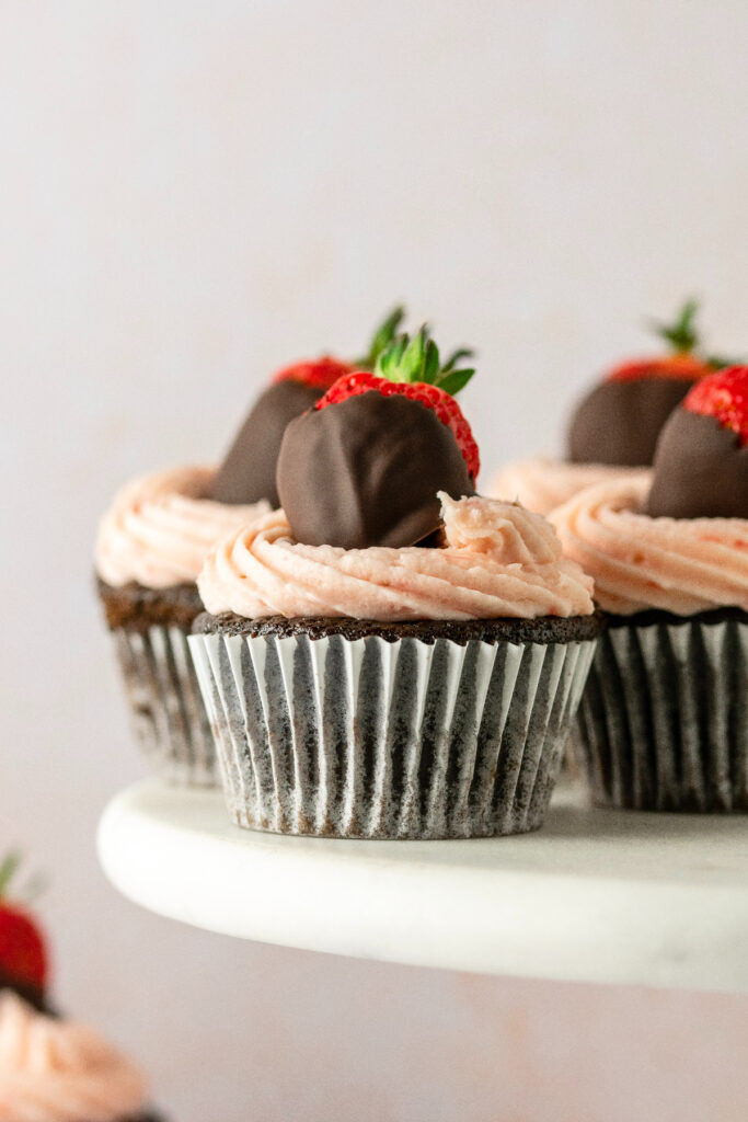 Chocolate cupcakes topped with strawberry frosting and a chocolate covered strawberry.