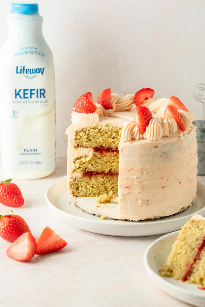 Banana cake with fresh strawberries and a bottle of Lifeway Kefir milk in the background.