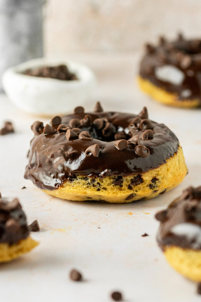 Baked chocolate donuts with mini chocolate chips on top.