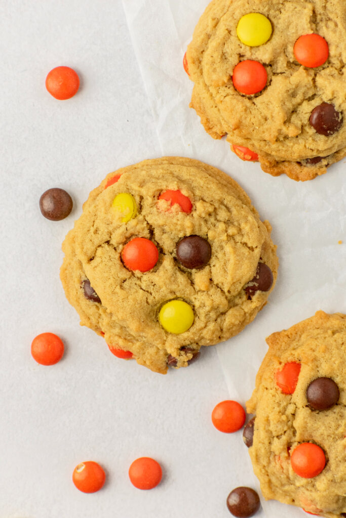 Three Reese's cookies with Reese's Pieces on the side.