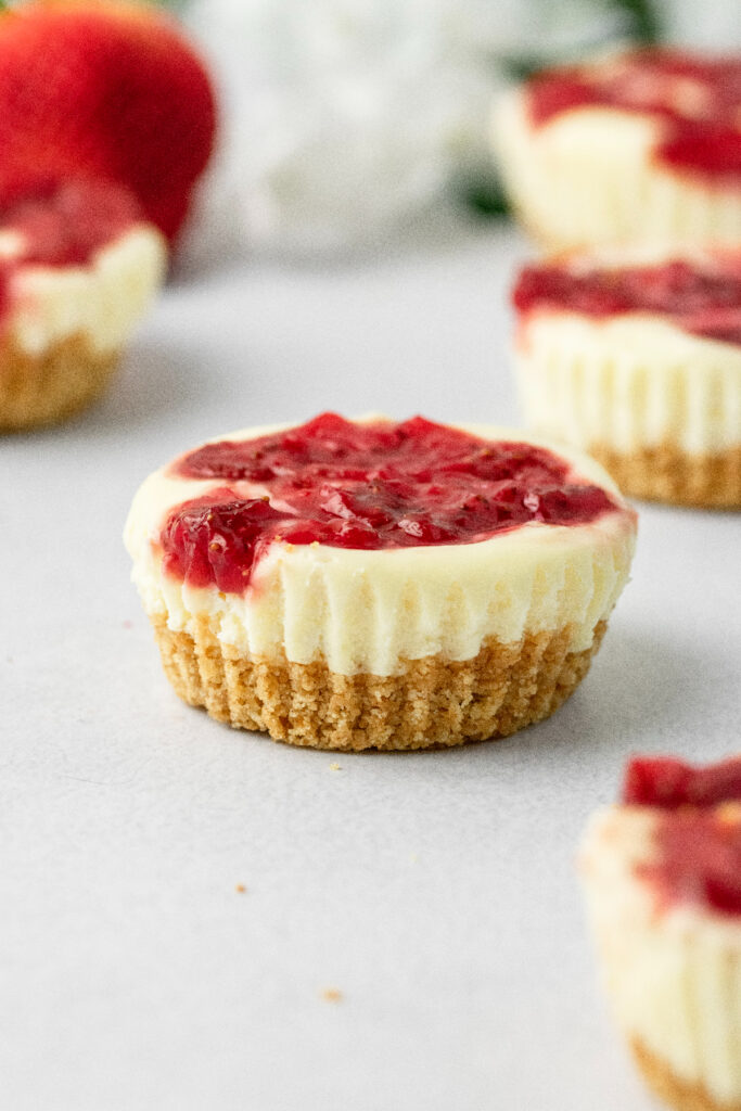 Strawberry swirl mini cheesecakes with fresh strawberries.