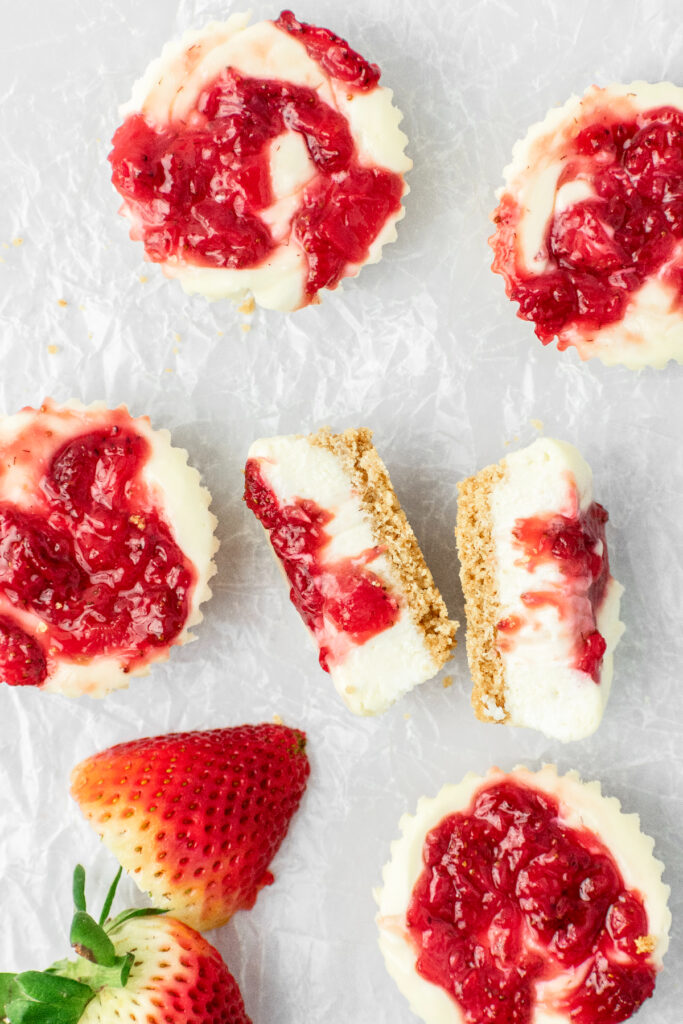 Mini strawberry cheesecakes lying flat on parchment paper.